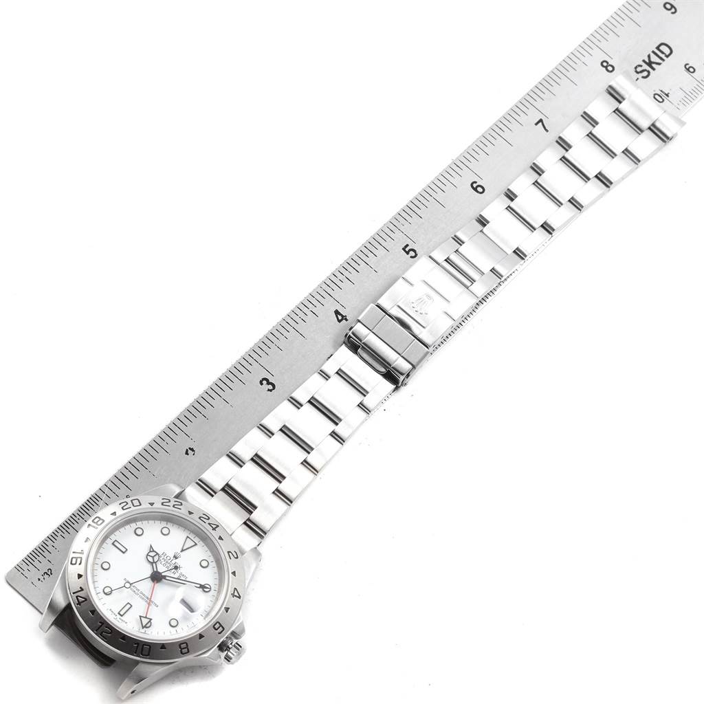 The image shows a Rolex Explorer 16570 Men's Stainless Steel White Dial 16570 Men's Stainless Steel White Dial watch lying flat next to a ruler, displaying its face, bezel, bracelet, and clasp.