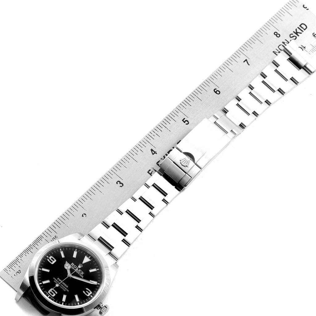 The image shows a Rolex Explorer 214270 Men's Stainless Steel Black Dial 214270 Men's Stainless Steel Black Dial watch lying flat with its bracelet aligned alongside a ruler for measurement.