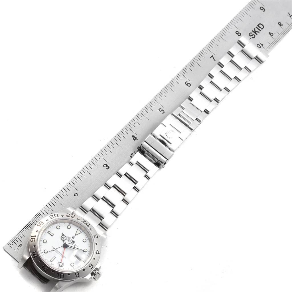 The image shows an overhead view of a Rolex Explorer 16570 Men's Stainless Steel White Dial 16570 Men's Stainless Steel White Dial watch beside a ruler, highlighting the watch face and stainless steel bracelet.