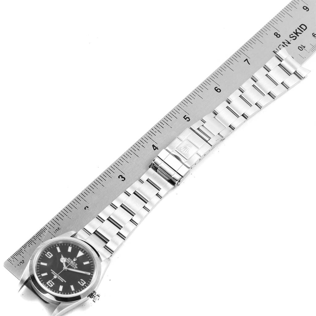 The image shows a Rolex Explorer 114270 Men's Stainless Steel Black Dial 114270 Men's Stainless Steel Black Dial watch laid flat next to a ruler, highlighting the watch face and stainless steel bracelet.