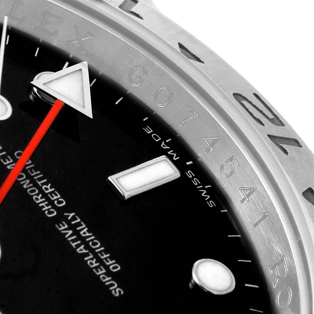 This close-up image of a Rolex Explorer 16570 Men's Stainless Steel Black Dial 16570 Men's Stainless Steel Black Dial watch shows a portion of the dial, the bezel with engraved numbers, and minute markers.
