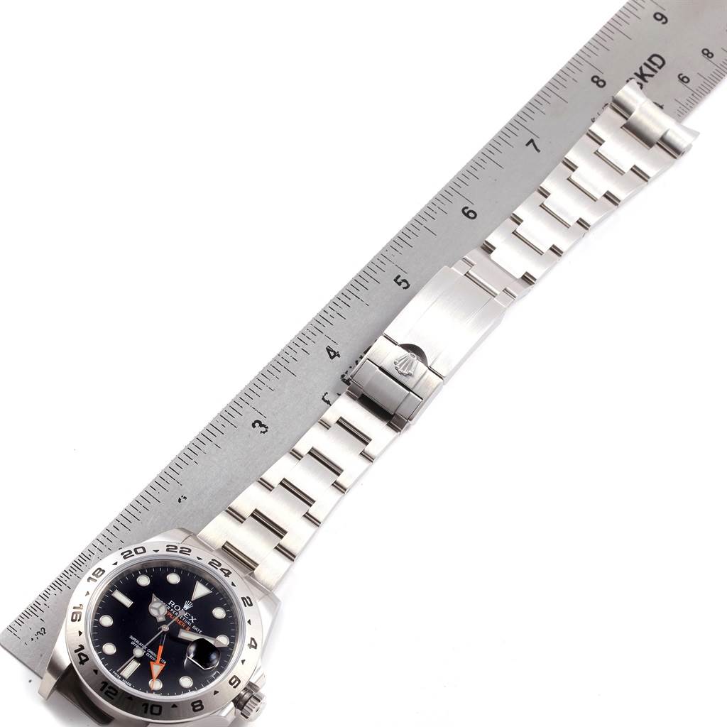 The Rolex Explorer 216570 Men's Stainless Steel Black Dial 216570 Men's Stainless Steel Black Dial watch is shown with its face and bracelet fully extended beside a measuring ruler.