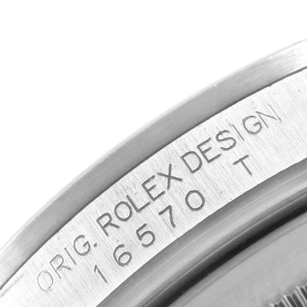 The image shows a close-up of the side of a Rolex Explorer 16570 Men
s Stainless Steel Black Dial 16570 Men
s Stainless Steel Black Dial watch, displaying the engraved model number 16570 and the designer attribution.