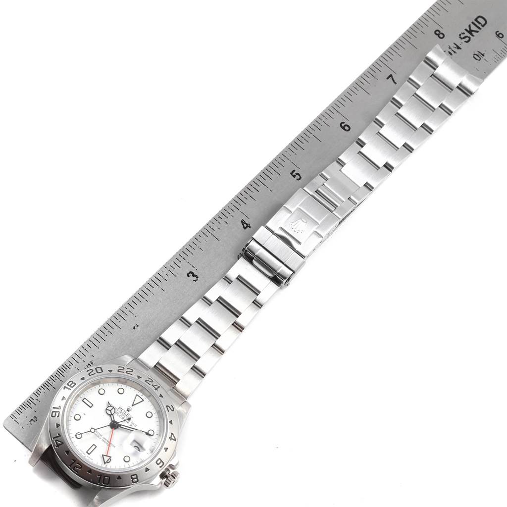 The image shows a Rolex Explorer 16570 Men
s Stainless Steel White Dial 16570 Men
s Stainless Steel White Dial watch laid flat next to a ruler, displaying its band and watch face from a top-down angle.