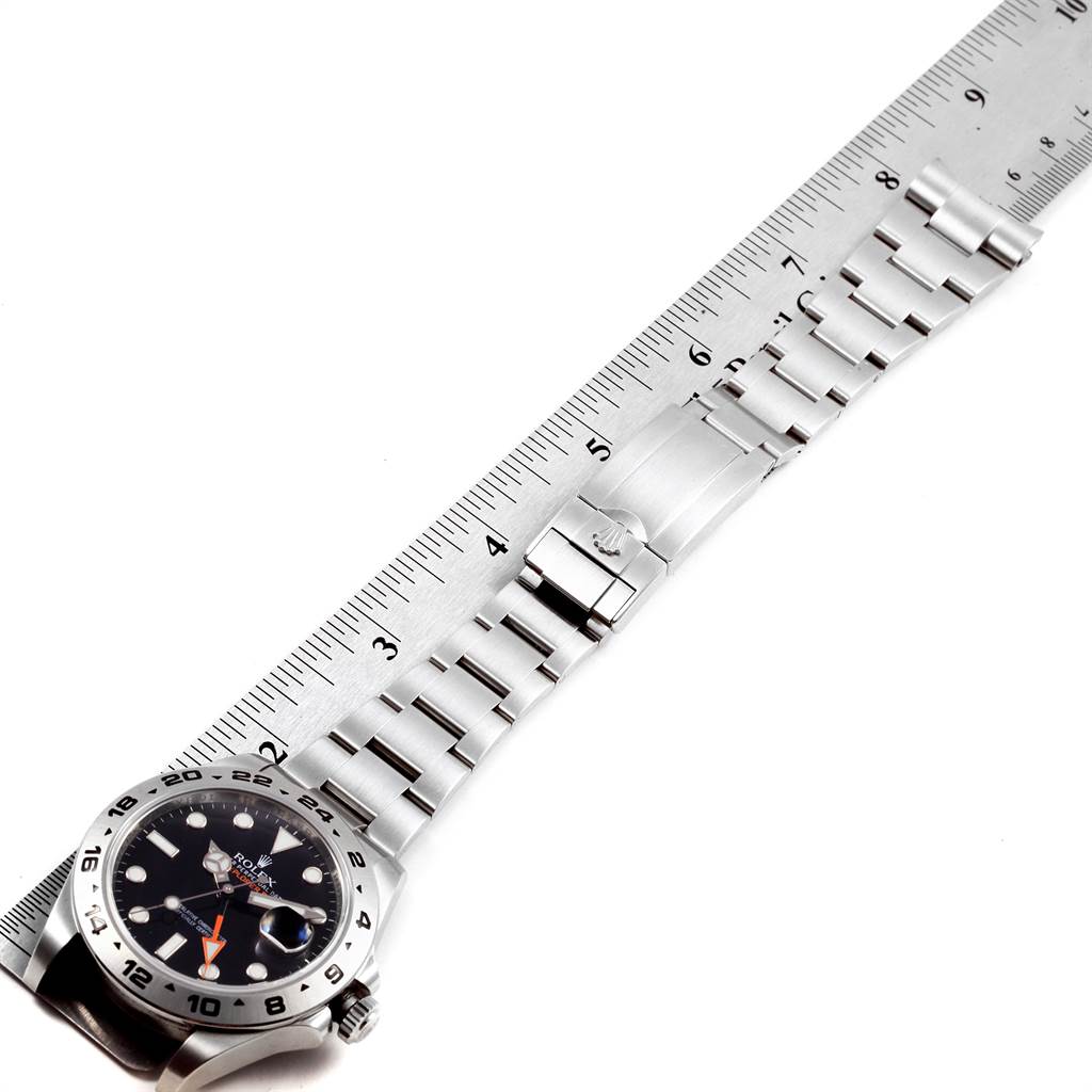 A Rolex Explorer 216570 Men's Stainless Steel Black Dial 216570 Men's Stainless Steel Black Dial watch is laid flat next to a ruler, showing its face and bracelet fully extended.
