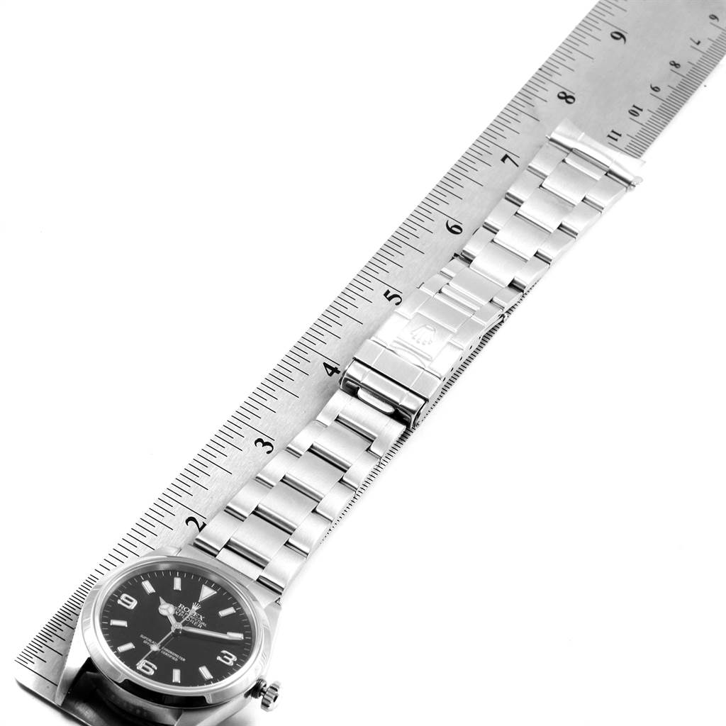 The image shows a top-down view of a Rolex Explorer 14270 Men's Stainless Steel Black Dial 14270 Men's Stainless Steel Black Dial watch with its metal bracelet aligned with a ruler for measurement.