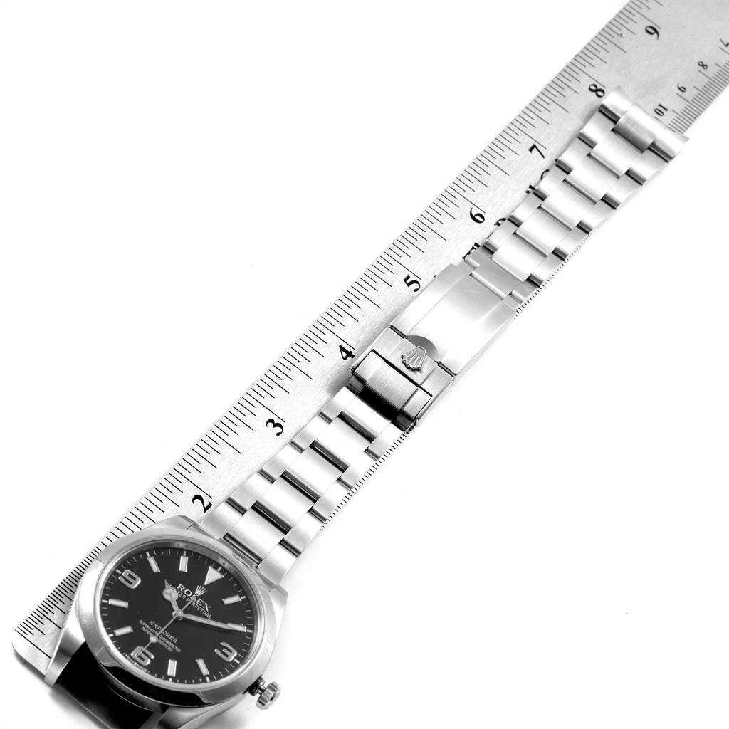 The image shows a top view of a Rolex Explorer 214270 Men's Stainless Steel Black Dial 214270 Men's Stainless Steel Black Dial watch, focusing on its face and bracelet, with a ruler for scale.