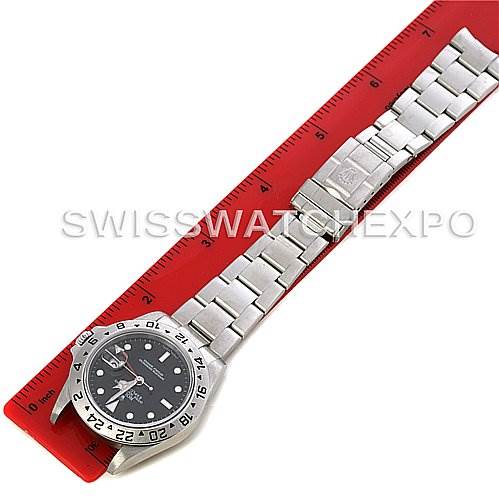 The image shows a Rolex Explorer 16570 Men's Stainless Steel Black Dial 16570 Men's Stainless Steel Black Dial watch laid flat with an angled view, featuring the watch face and stainless steel bracelet alongside a ruler.