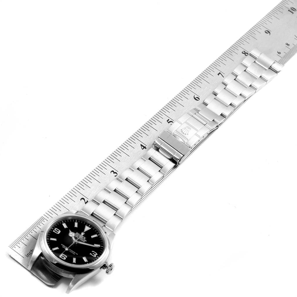 The image shows a Rolex Explorer 114270 Men's Stainless Steel Black Dial 114270 Men's Stainless Steel Black Dial watch laid flat against a ruler, highlighting its bracelet and clasp.
