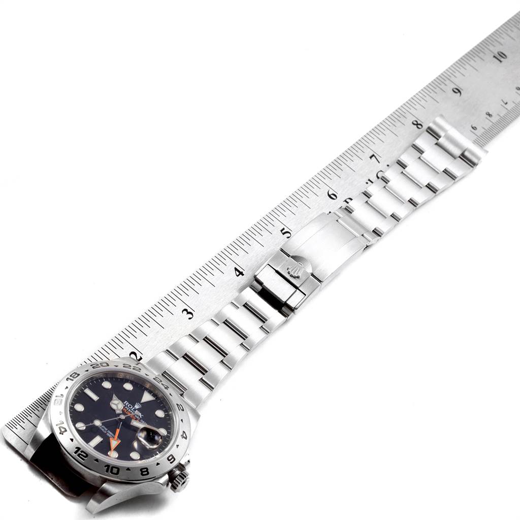 The image shows a Rolex Explorer 216570 Men's Stainless Steel Black Dial 216570 Men's Stainless Steel Black Dial watch laid flat beside a ruler, showcasing both the face and the metal strap.