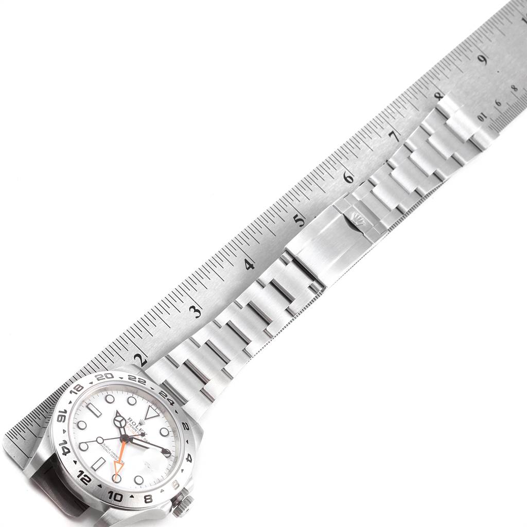 The Rolex Explorer 216570 Men's Stainless Steel White Dial 216570 Men's Stainless Steel White Dial watch is shown from a top-down angle, featuring the face, bezel, and metal bracelet next to a ruler.