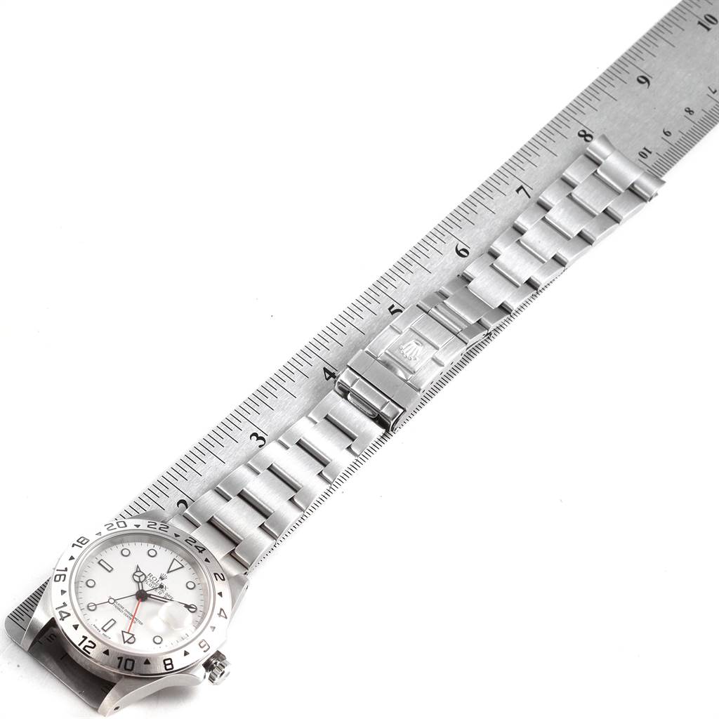 The image shows a top-down view of a Rolex Explorer 16570 Men's Stainless Steel White Dial 16570 Men's Stainless Steel White Dial watch with a ruler measuring its metal bracelet.
