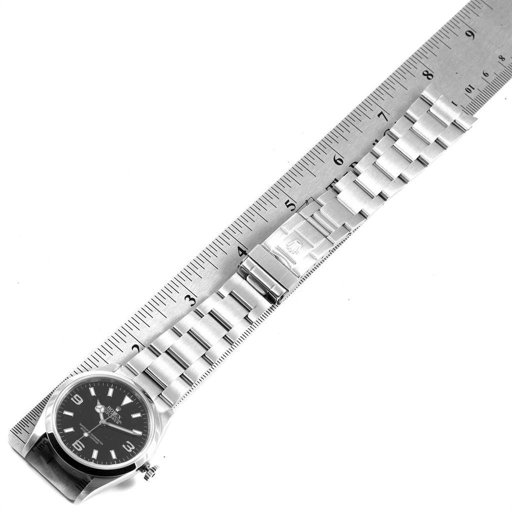 The image shows the Rolex Explorer 114270 Men's Stainless Steel Black Dial 114270 Men's Stainless Steel Black Dial watch laying flat, with its face, bezel, bracelet, and clasp visible alongside a ruler.