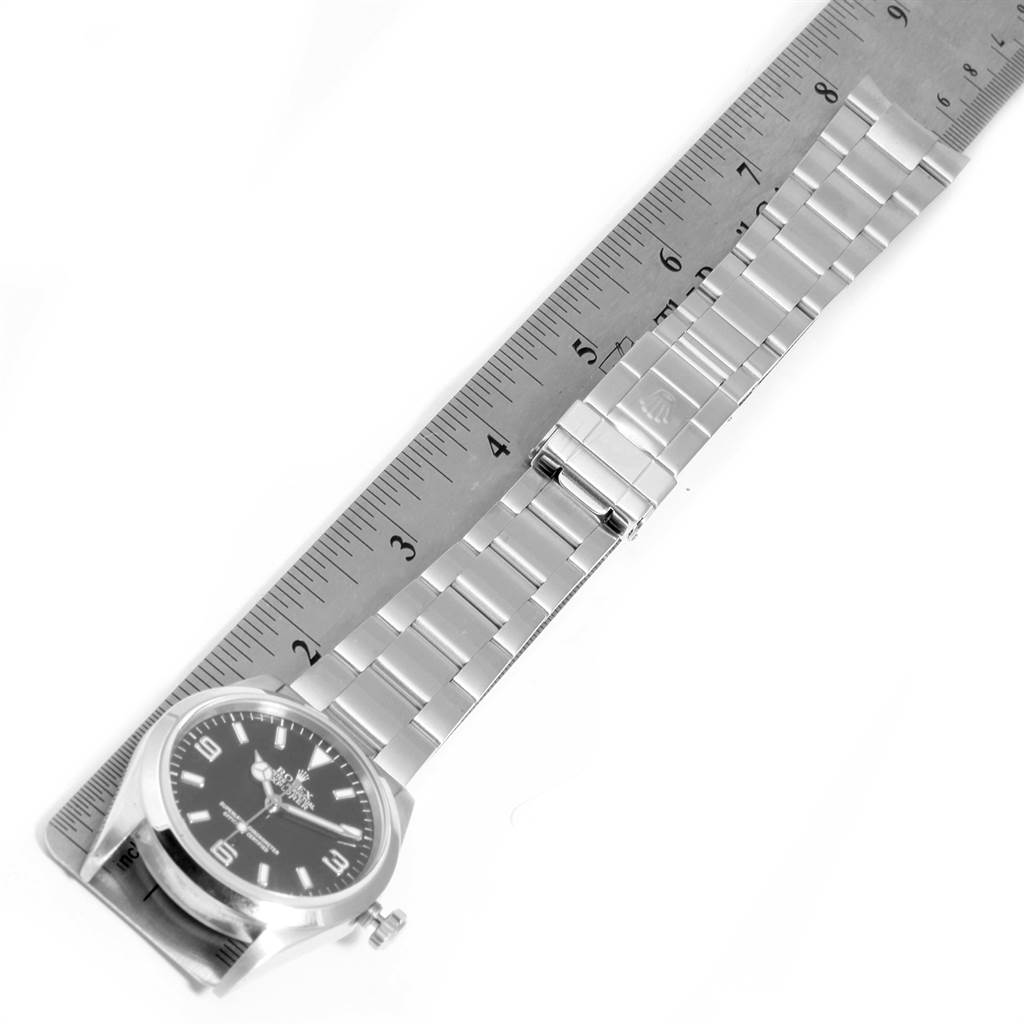 The image shows a Rolex Explorer 114270 Men's Stainless Steel Black Dial 114270 Men's Stainless Steel Black Dial watch with its metal bracelet laid beside a ruler for measurement.