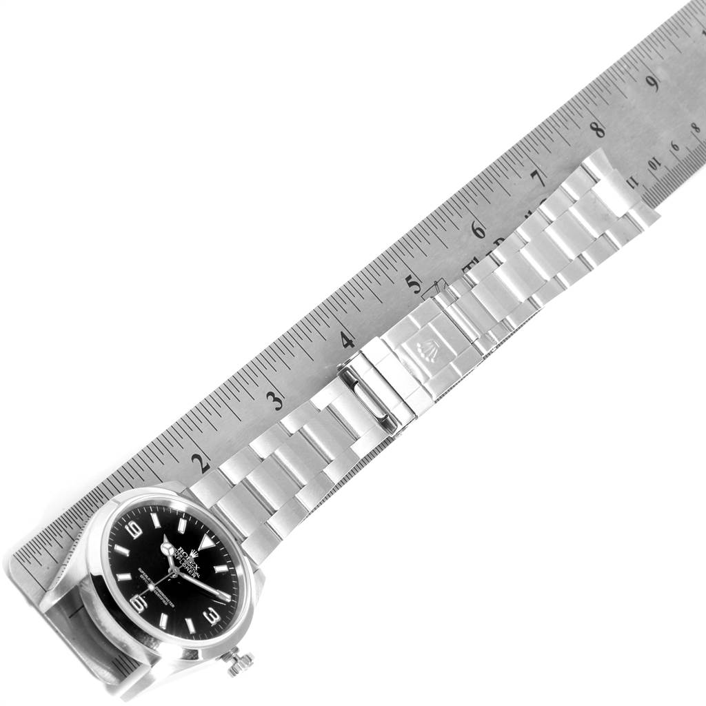 The image shows a top view of a Rolex Explorer 114270 Men's Stainless Steel Black Dial 114270 Men's Stainless Steel Black Dial watch with its bracelet extended next to a ruler for scale.