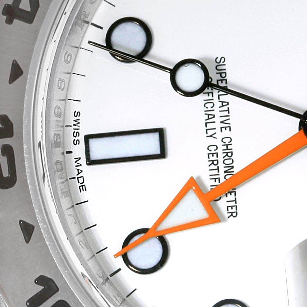 This close-up of a Rolex Explorer 216570 Men's Stainless Steel White Dial 216570 Men's Stainless Steel White Dial watch shows part of the dial, including the hour markers, hands, and part of the bezel.