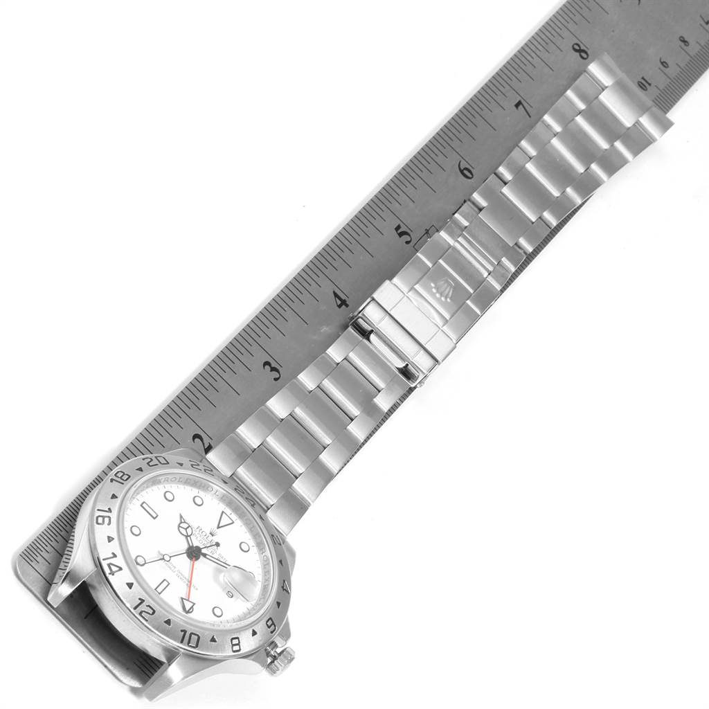 The image shows a Rolex Explorer 16570 Men's Stainless Steel White Dial 16570 Men's Stainless Steel White Dial watch positioned at an angle, with the watch face and part of the metal bracelet visible, alongside a ruler for scale.