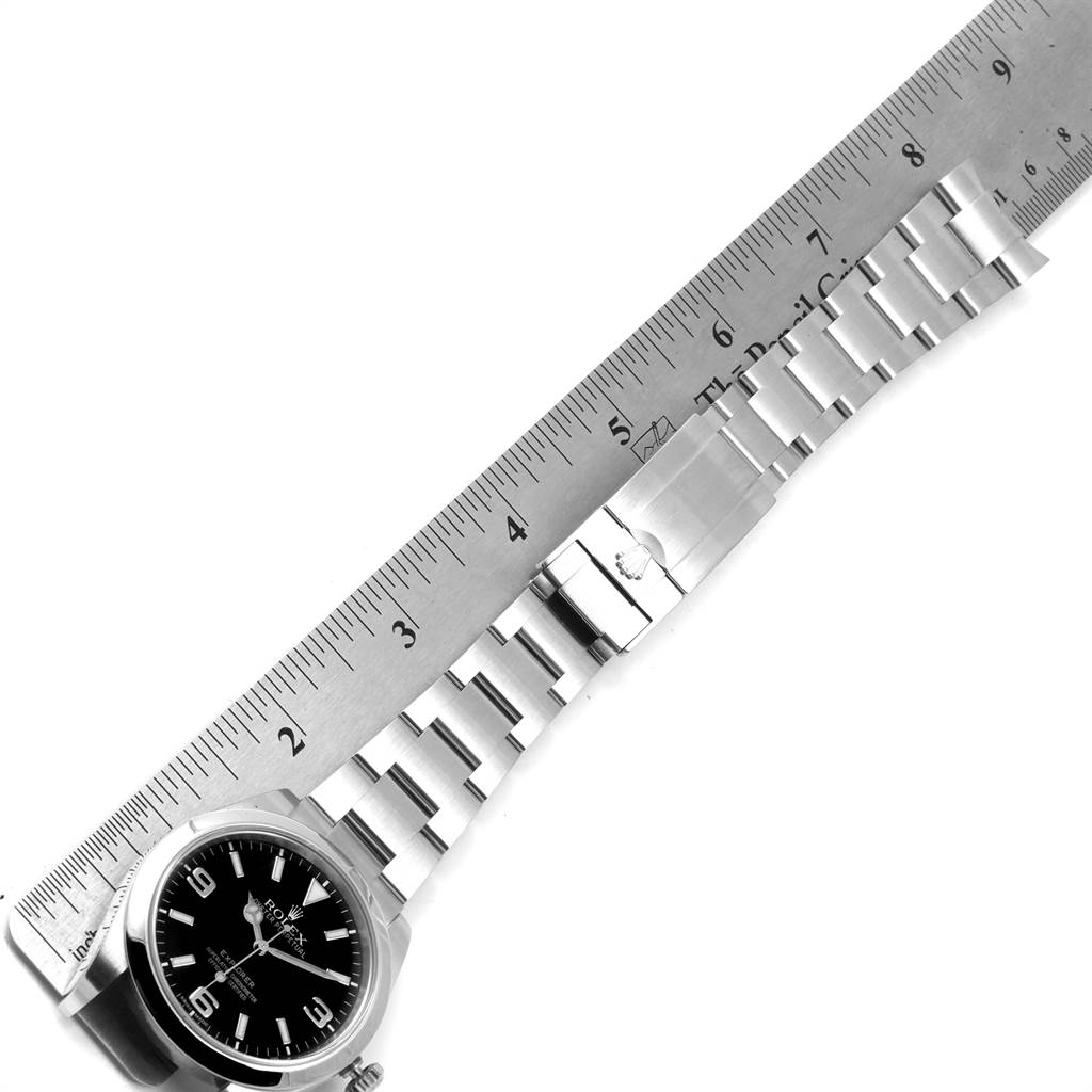 The image shows a Rolex Explorer 214270 Men's Stainless Steel Black Dial 214270 Men's Stainless Steel Black Dial watch placed next to a ruler, displaying the dial and bracelet.