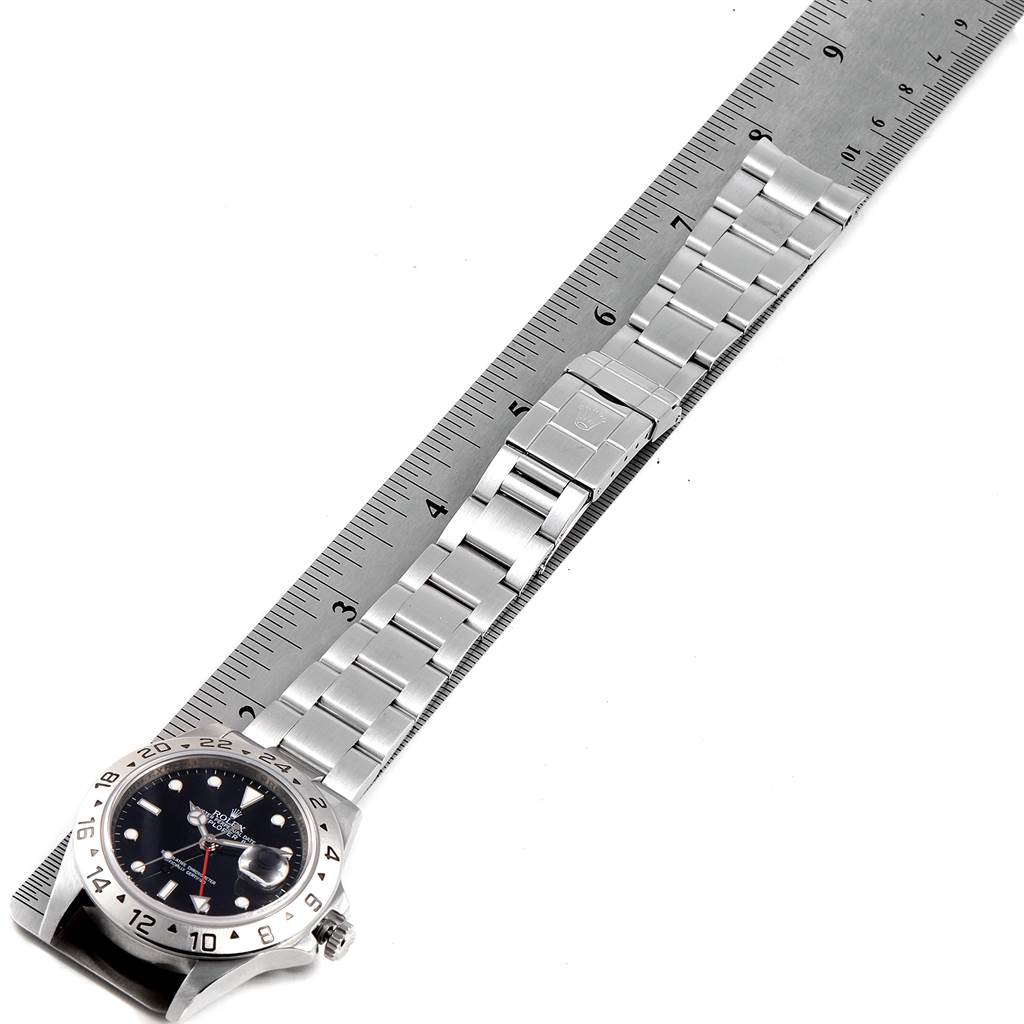 The image shows an overhead view of a Rolex Explorer 16570 Men's Stainless Steel Black Dial 16570 Men's Stainless Steel Black Dial watch with a metal bracelet, beside a ruler.