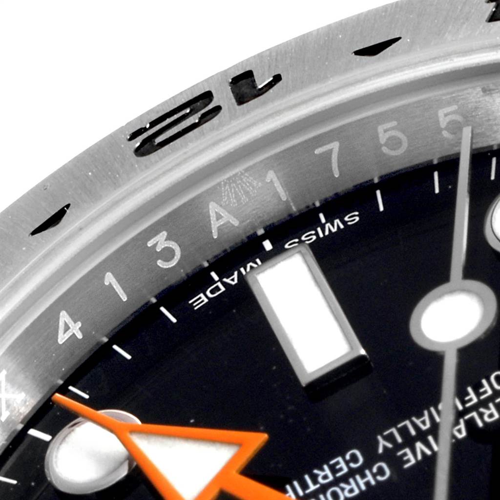 A close-up view of the Rolex Explorer 216570 Men's Stainless Steel Black Dial 216570 Men's Stainless Steel Black Dial watch's bezel, part of the dial, and the orange hour hand.