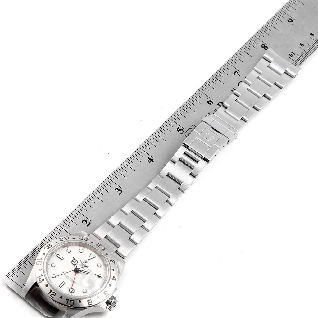 The image shows a Rolex Explorer 16570 Men's Stainless Steel White Dial 16570 Men's Stainless Steel White Dial watch with a metal bracelet next to a ruler, displaying its face, bezel, and bracelet length.