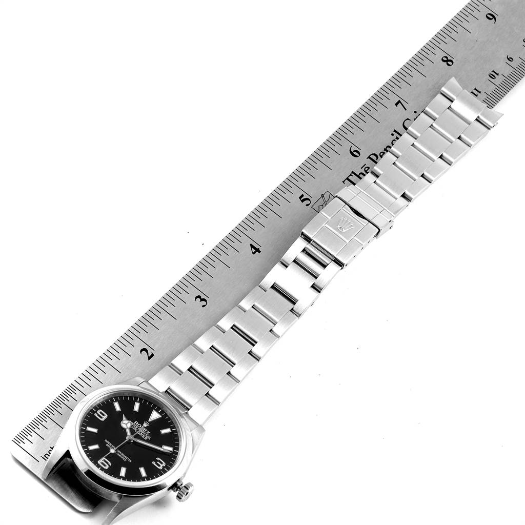 The image shows a top view of a Rolex Explorer 114270 Men's Stainless Steel Black Dial 114270 Men's Stainless Steel Black Dial model watch alongside a ruler, displaying its full bracelet and face.