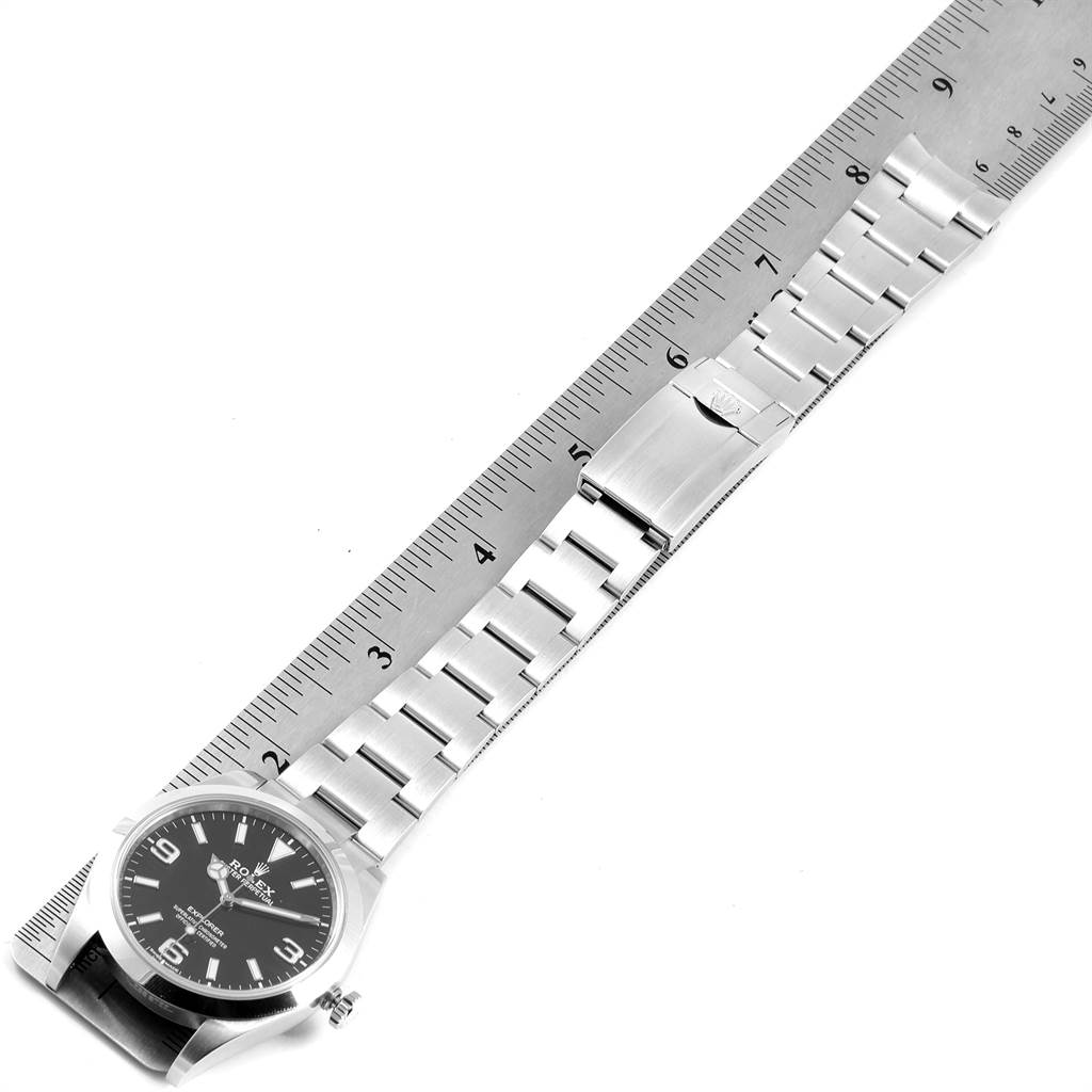 The image shows a Rolex Explorer 214270 Men's Stainless Steel Black Dial 214270 Men's Stainless Steel Black Dial watch laid flat next to a ruler, displaying its face, band, and clasp.