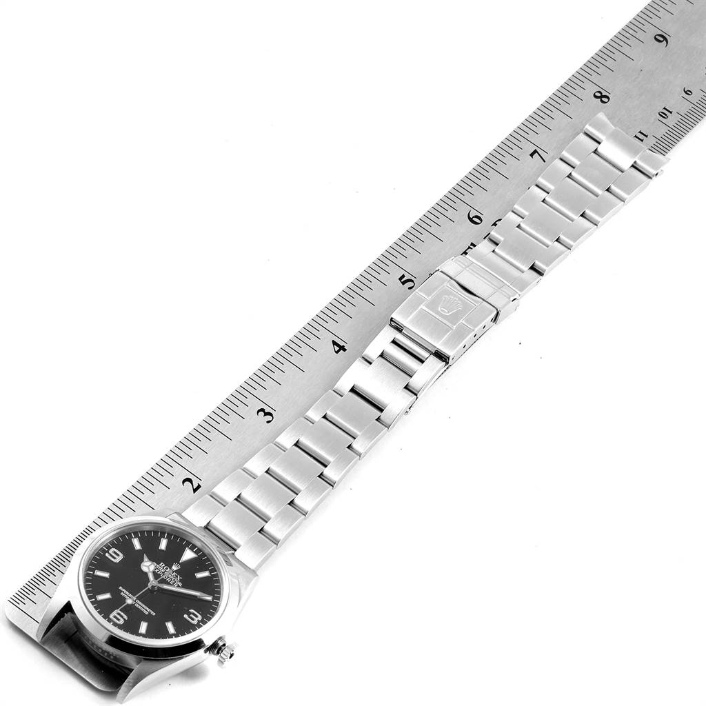 The image shows a Rolex Explorer 114270 Men's Stainless Steel Black Dial 114270 Men's Stainless Steel Black Dial watch laid flat alongside a ruler, showcasing the face, bezel, crown, and bracelet.