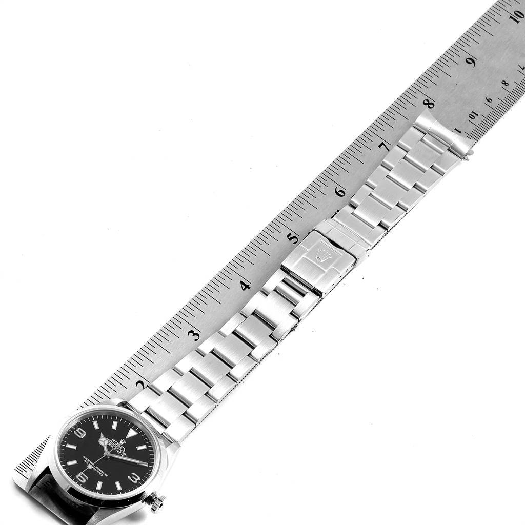 The image shows a Rolex Explorer 14270 Men's Stainless Steel Black Dial 14270 Men's Stainless Steel Black Dial watch laid flat with a metal ruler, highlighting the watch face and bracelet.