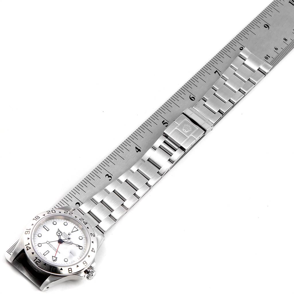 The Rolex Explorer 16570 Men's Stainless Steel White Dial 16570 Men's Stainless Steel White Dial watch is shown from a top view, displaying its face, bezel, and metal bracelet next to a ruler.
