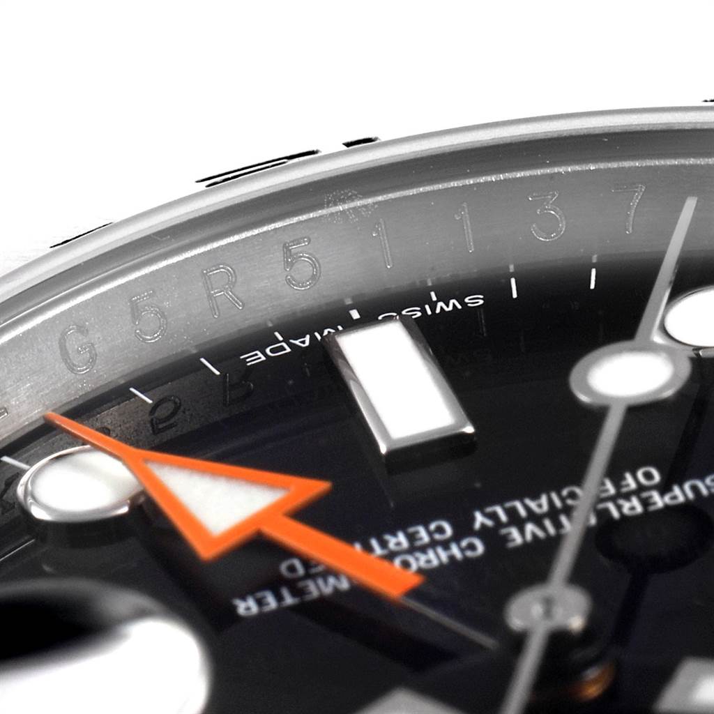 The image shows a close-up view of the dial and bezel of a Rolex Explorer 216570 Men's Stainless Steel Black Dial 216570 Men's Stainless Steel Black Dial watch, highlighting the engraved serial number and orange hand.