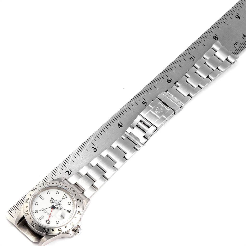 The image shows a top-down view of a Rolex Explorer 16570 Men
s Stainless Steel White Dial 16570 Men
s Stainless Steel White Dial watch, including its face and entire bracelet, alongside a ruler.