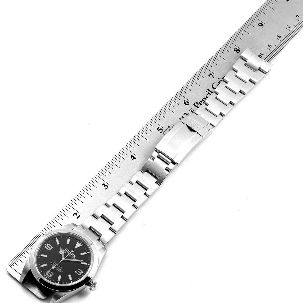 The image shows a Rolex Explorer 214270 Men's Stainless Steel Black Dial 214270 Men's Stainless Steel Black Dial watch laid flat alongside a ruler, displaying its watch face and metal bracelet.