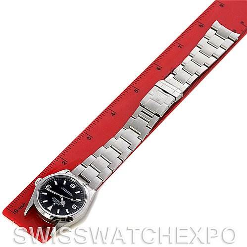 The Rolex Explorer 114270 Men's Stainless Steel Black Dial 114270 Men's Stainless Steel Black Dial watch is angled diagonally, showing the face, bracelet, and clasp, with a red ruler for scale.