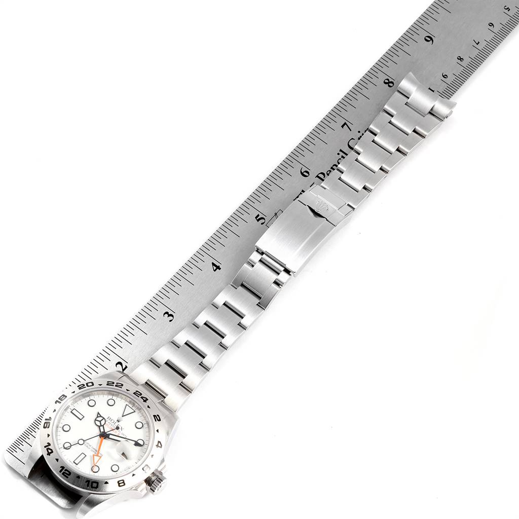 This image shows a Rolex Explorer 216570 Men's Stainless Steel White Dial 216570 Men's Stainless Steel White Dial watch laid flat alongside a ruler, displaying its face and metal bracelet.