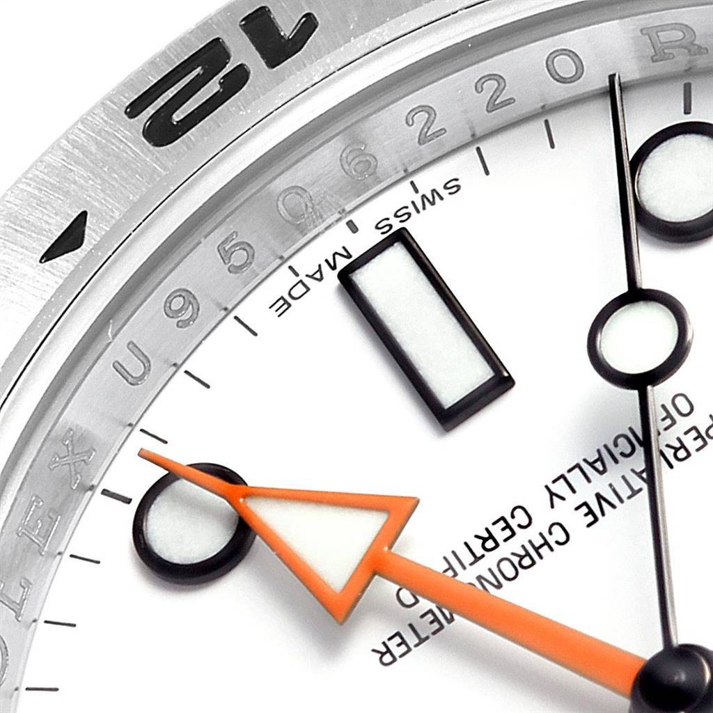 This close-up angle of the Rolex Explorer 216570 Men's Stainless Steel White Dial 216570 Men's Stainless Steel White Dial watch shows part of the dial, including hour markers, the orange hand, and numbers on the bezel.