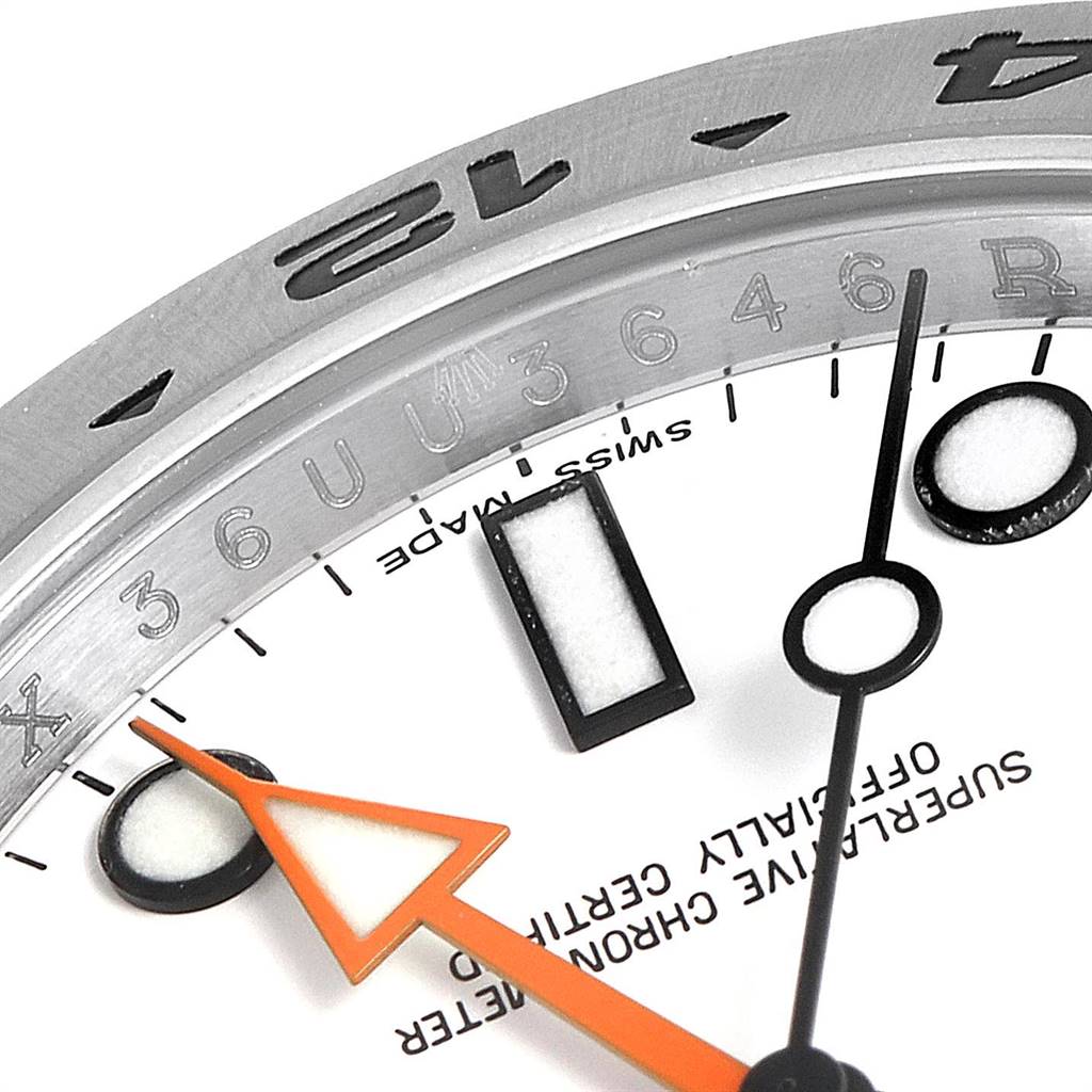 This close-up image of the Rolex Explorer 216570 Men's Stainless Steel White Dial 216570 Men's Stainless Steel White Dial shows part of the dial, bezel, hour markers, and orange hand at an angle.