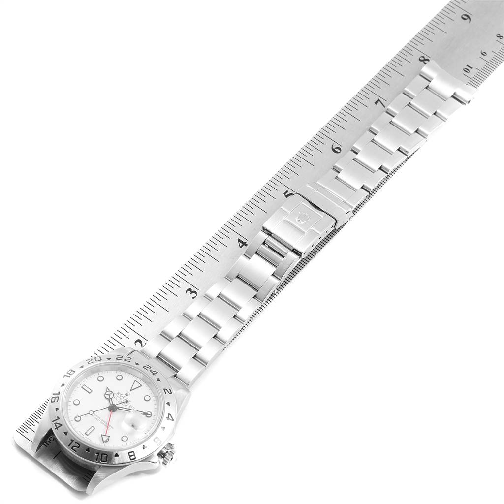 This image shows a Rolex Explorer 16570 Men's Stainless Steel White Dial 16570 Men's Stainless Steel White Dial model watch with its dial, bezel, and bracelet laid out next to a ruler for measurement.