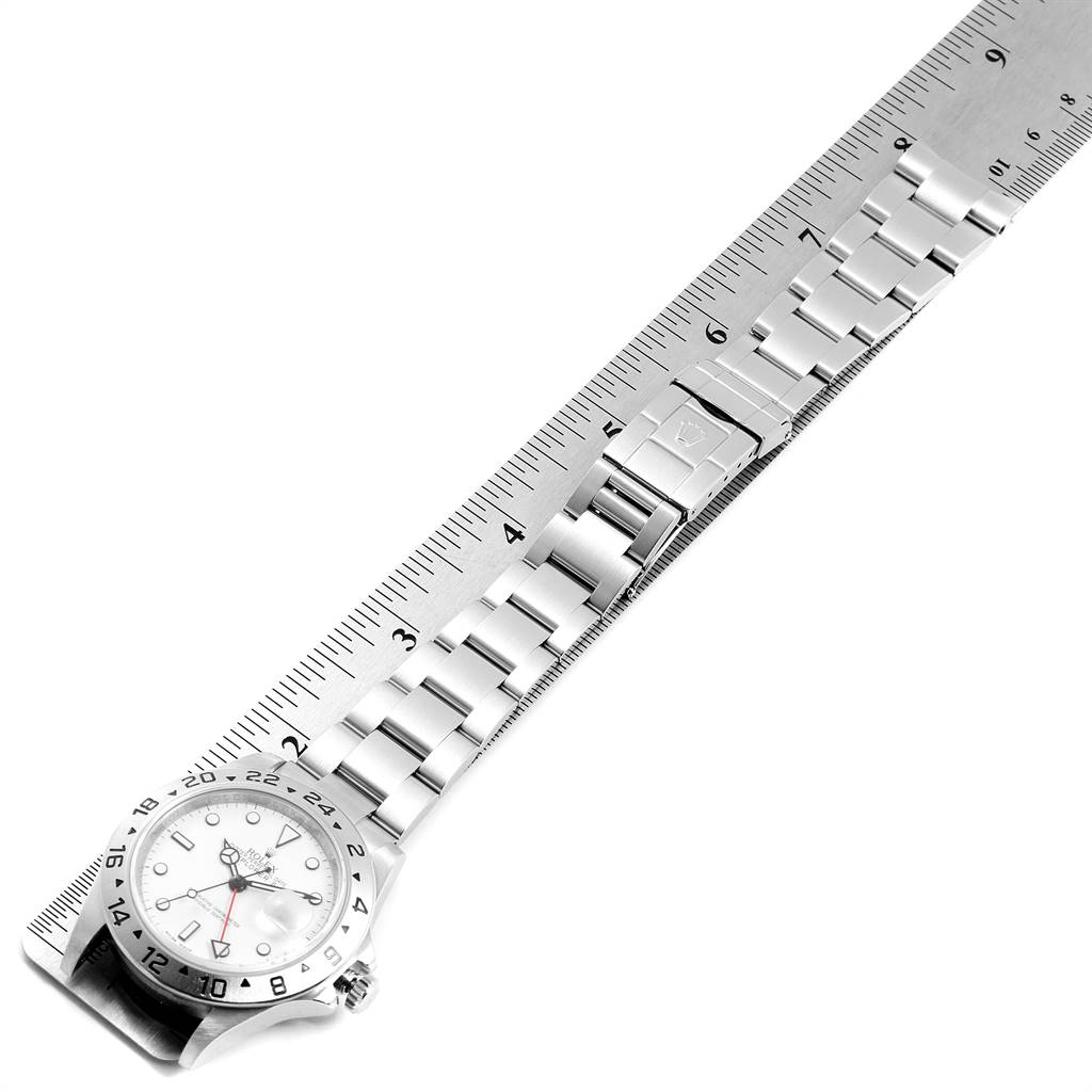 The image shows a Rolex Explorer 16570 Men's Stainless Steel White Dial 16570 Men's Stainless Steel White Dial watch laid flat next to a ruler, highlighting its bracelet, clasp, and dial.