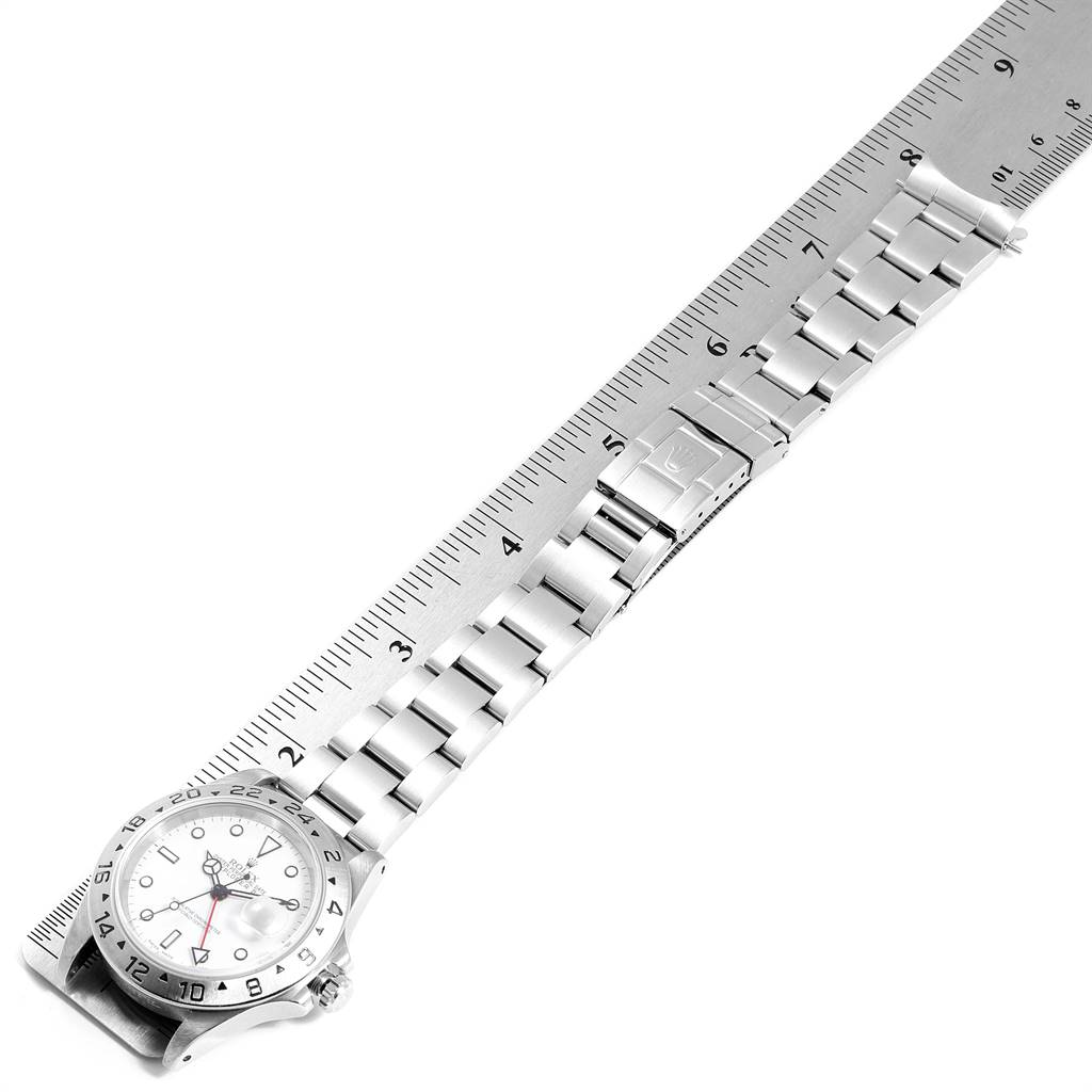 The Rolex Explorer 16570 Men's Stainless Steel White Dial 16570 Men's Stainless Steel White Dial watch is shown at an angle highlighting the face, bezel, and full metal band alongside a ruler for scale.