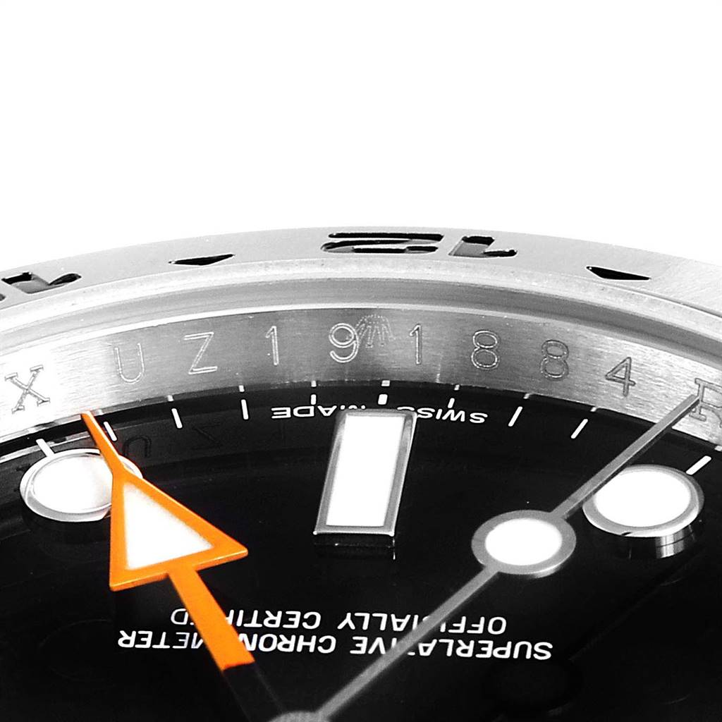 This close-up image of a Rolex Explorer 216570 Men's Stainless Steel Black Dial 216570 Men's Stainless Steel Black Dial watch showcases the dial, orange GMT hand, bezel, and part of the case.