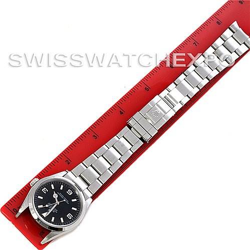 The image shows a top-down view of the Rolex Explorer 114270 Men's Stainless Steel Black Dial 114270 Men's Stainless Steel Black Dial watch laid flat on a red ruler.