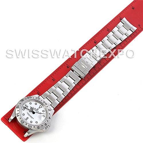 The image shows a top-down view of a Rolex Explorer 16570 Men
s Stainless Steel White Dial 16570 Men
s Stainless Steel White Dial watch, displaying the entire watch including the face and bracelet, along with a red measuring ruler.