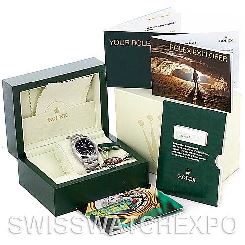 The image shows a Rolex Explorer 114270 Men's Stainless Steel Black Dial 114270 Men's Stainless Steel Black Dial watch at an angled view from the top, along with its green box, manuals, and warranty card.