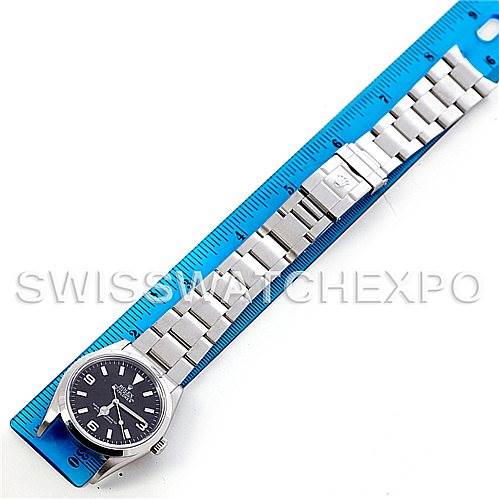 The Rolex Explorer 114270 Men's Stainless Steel Black Dial 114270 Men's Stainless Steel Black Dial watch is shown from a top-down angle, displaying its full bracelet and face alongside a blue ruler.