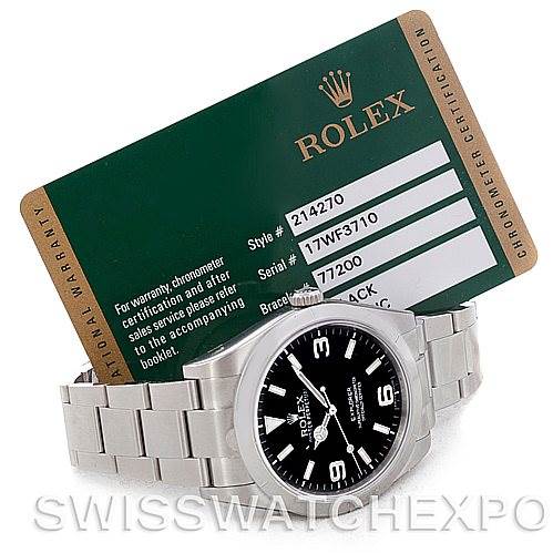 The image shows a Rolex Explorer 214270 Men
s Stainless Steel Black Dial 214270 Men
s Stainless Steel Black Dial watch along with its certification card, tilted at an angle highlighting the front and bracelet.
