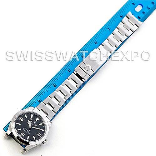 The image shows a Rolex Explorer 214270 Men's Stainless Steel Black Dial 214270 Men's Stainless Steel Black Dial watch laid flat with the dial face up next to a blue ruler for measurement.