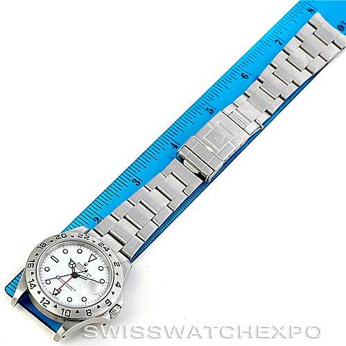 The image shows a full view of the Rolex Explorer 16570 Men's Stainless Steel White Dial 16570 Men's Stainless Steel White Dial watch with its stainless steel bracelet next to a blue measuring ruler.