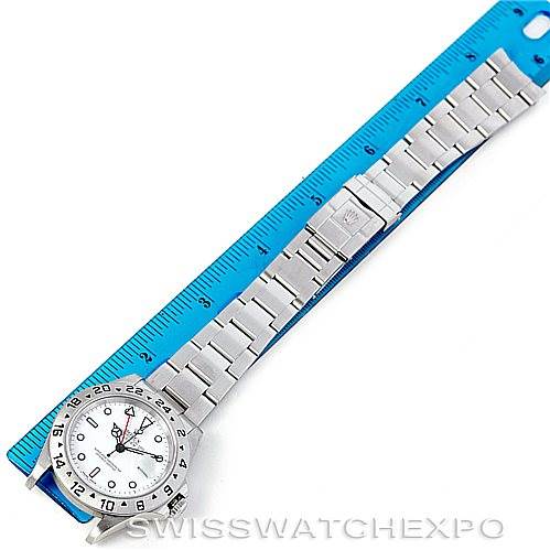 The image shows a Rolex Explorer 16570 Men's Stainless Steel White Dial 16570 Men's Stainless Steel White Dial watch laid flat next to a blue ruler, highlighting the face, bezel, and bracelet of the watch.