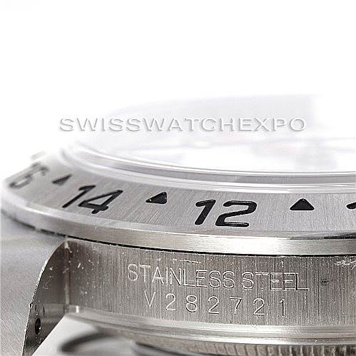 This close-up image of a Rolex Explorer 16570 Men's Stainless Steel White Dial 16570 Men's Stainless Steel White Dial watch shows its bezel, part of the dial, and engravings on the stainless steel case.